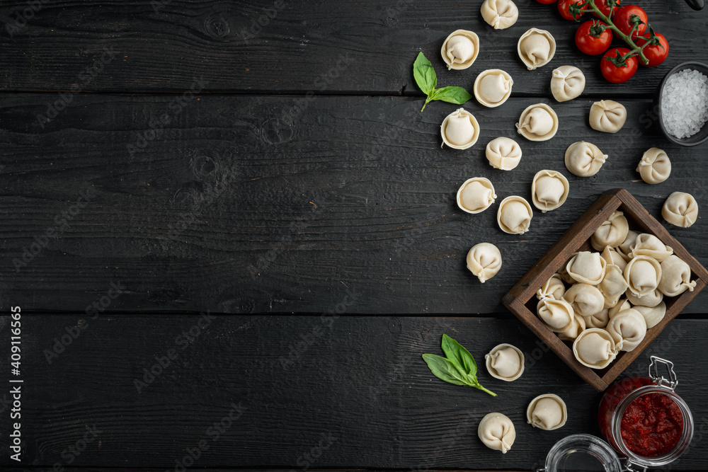 Tasty raw tortellini with flour and basil, on black wooden table background , top view flat lay , with copyspace  and space for text