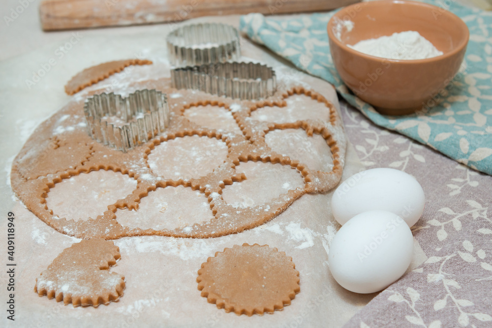 Cutting out heart-shaped cookies from raw dough using cookie cutters. Cutting out heart-shaped cookies from raw dough using cookie cutters.