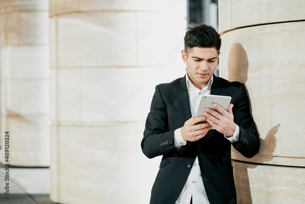 banker business man employee working in a business center in a bank. holds a tablet and writes a message. the man is dark-haired of European appearance. business suit and white shirt banker business man employee working in a business center in a bank. holds a tablet and writes a message. the man is dark-haired of European appearance. business suit and white shirt