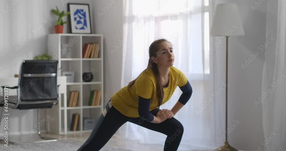 young woman is squatting at morning workout at home, doing gymnastics and aerobic for good physical activity young woman is squatting at morning workout at home, doing gymnastics and aerobic for good physical activity
