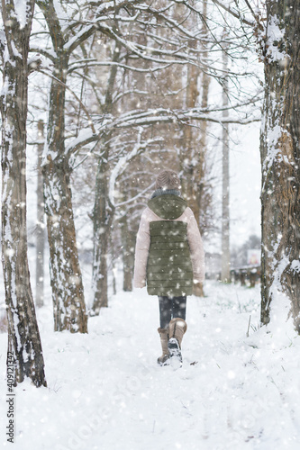 teen girl walks on a snow-covered path in winter, a teenage boy and a girl, a snowstorm © soleg