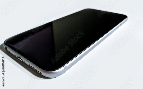 Black-gray mobile phone laying down on a white surface