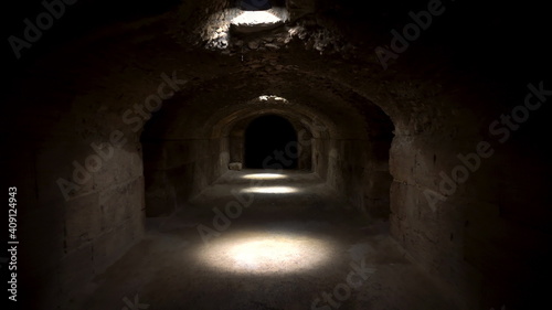 Passage through a dark roman basement. Basement under the Amphitheater in El Jem, Tunis. Ancient roman building. The camera moves away © Vital9c