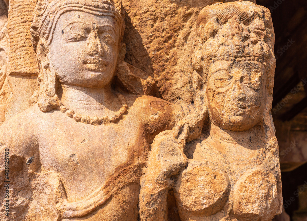 Aihole, Karnataka, India - November 7, 2013: Durga Gudi or Temple. Chest and face closeup of damaged red stone sculpture of couple with her breast cut off.
