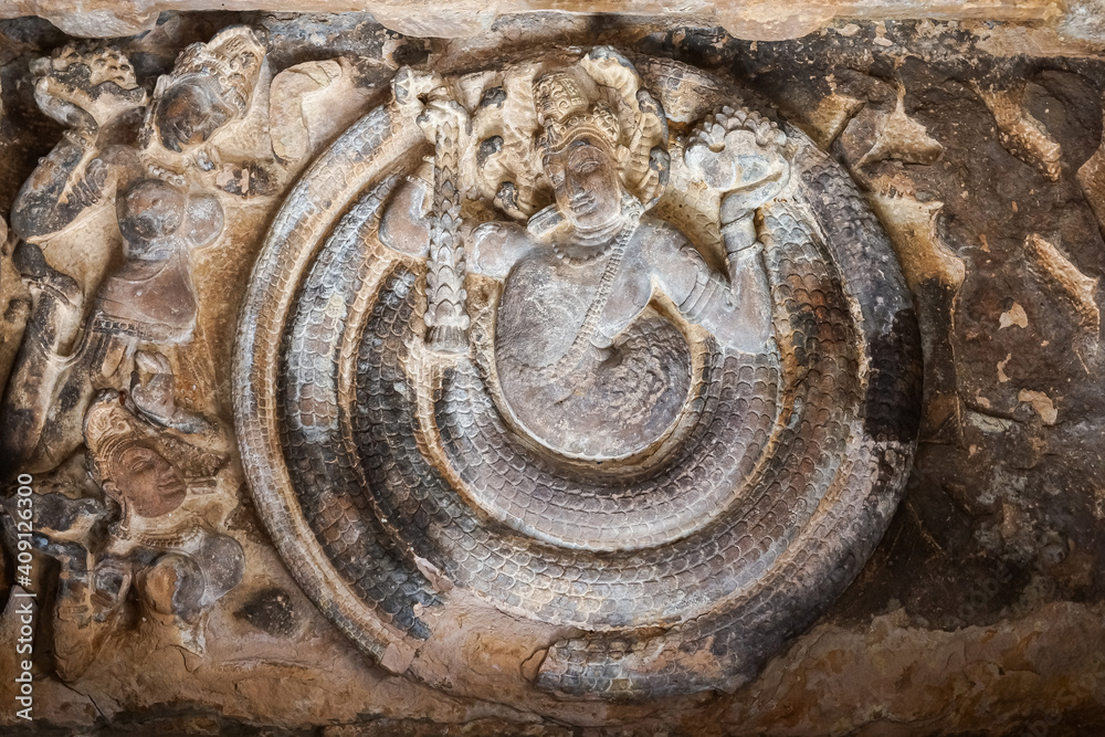 Aihole, Karnataka, India - November 7, 2013: Durga Gudi or Temple. Detail of Mandapam ceiling showing Vishnu surrounded by snake while his 2 wives look on.