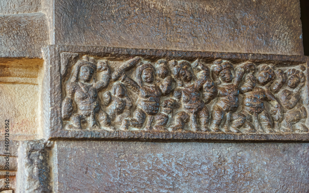 Aihole, Karnataka, India - November 7, 2013: Durga Gudi or Temple. Gray stone row or line of human figures fresco.