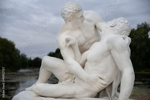 Very old sculpture of a couple of men embracing in white marble