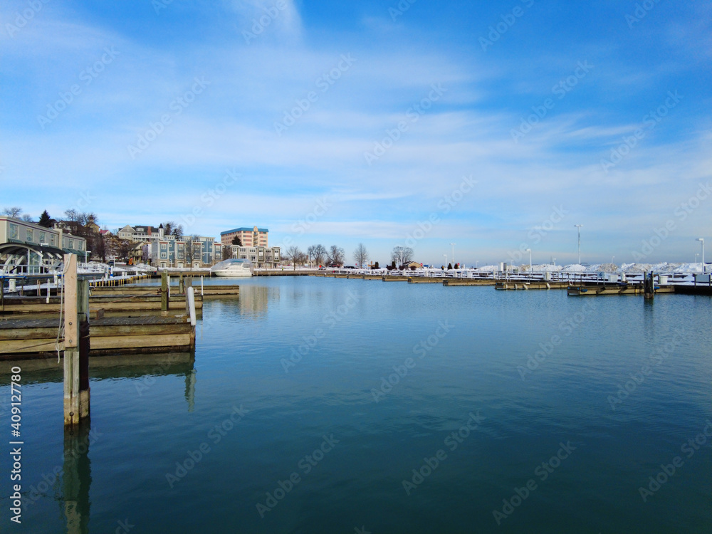 Calm marina waters on the lake shore in the Winter with light clouds and blue waters.
