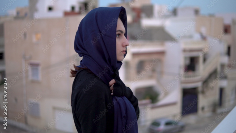 Young woman in the Arab headscarf. A woman is walking on the roof. On the roof of the house against the backdrop of Arab houses.
