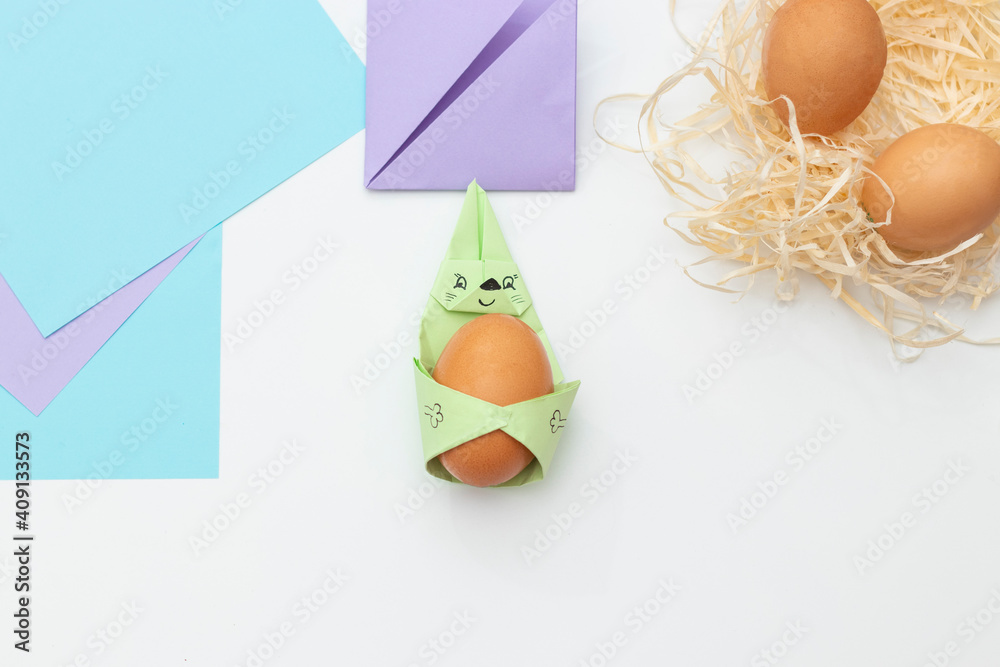 DIY Children's Easter craft bunny with an egg. Easter paper step by step instructions. Step 20. Happy bunny holds egg. Children's Art Project, needlework, crafts for children, springtime.