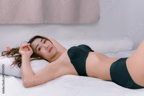 Sexy Asian woman wearing a black bikini On a white bed