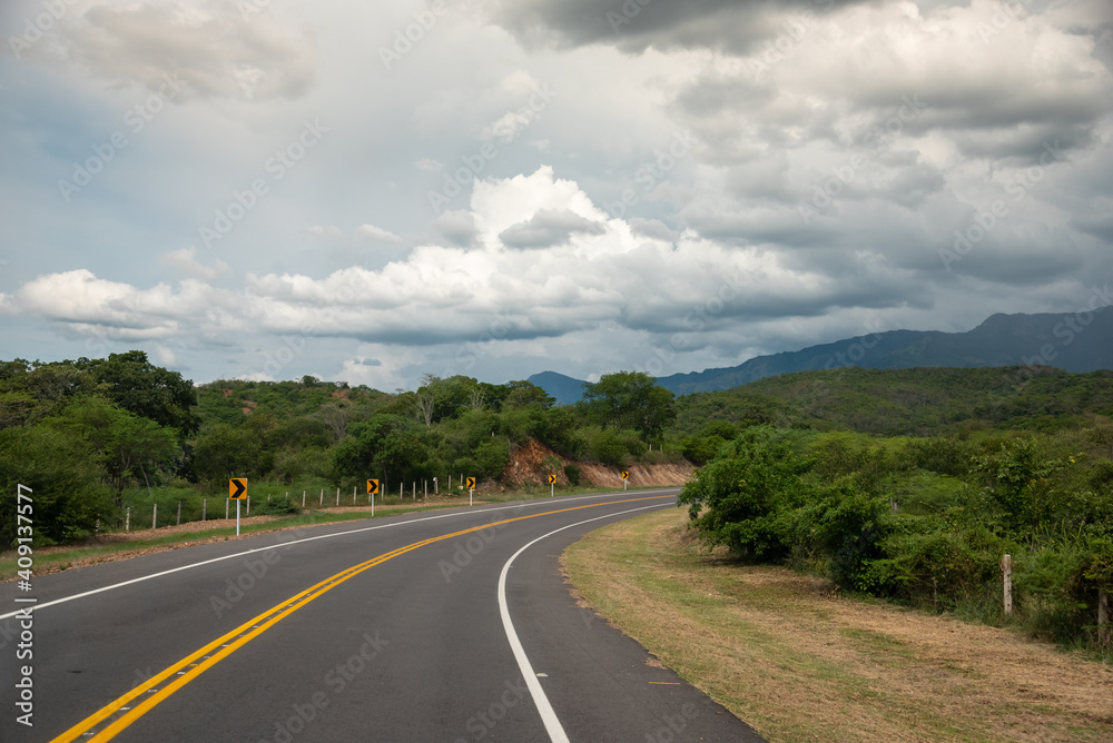 Curve of a road in Colombian rural landscape with some colonies in the background