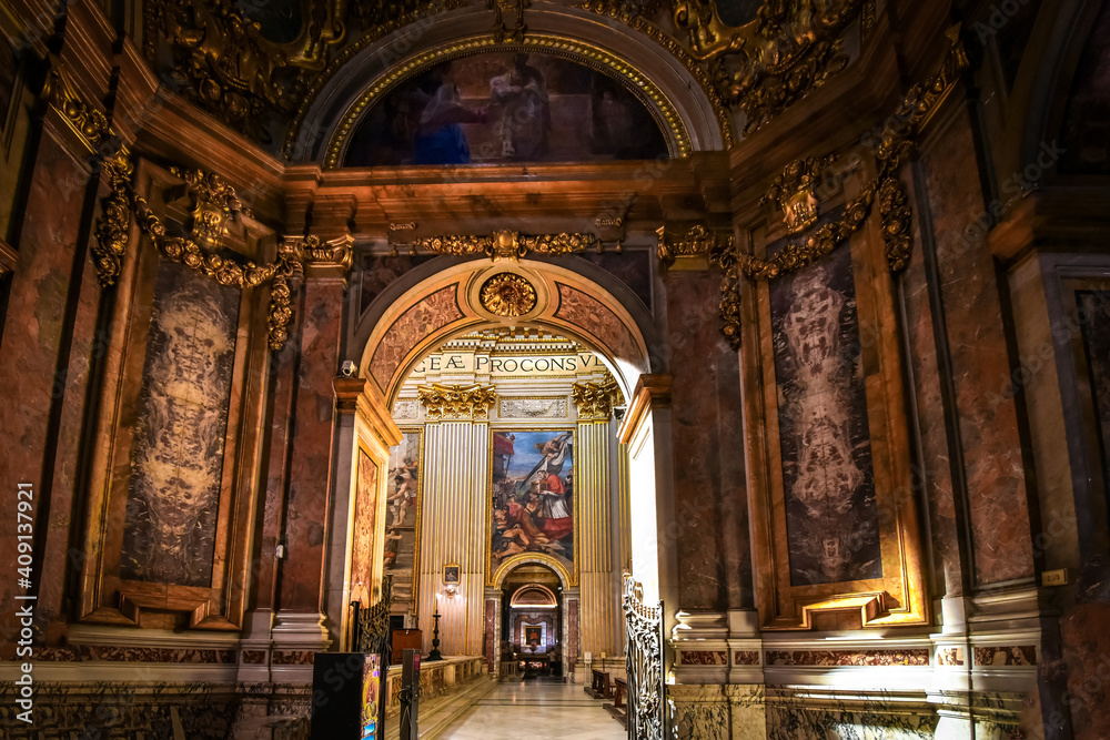 View looking through doorway of a small chapel to the golden, ornately decorated interior apse of the Basilica of Sant'Andrea della Valle in Rome, Italy.