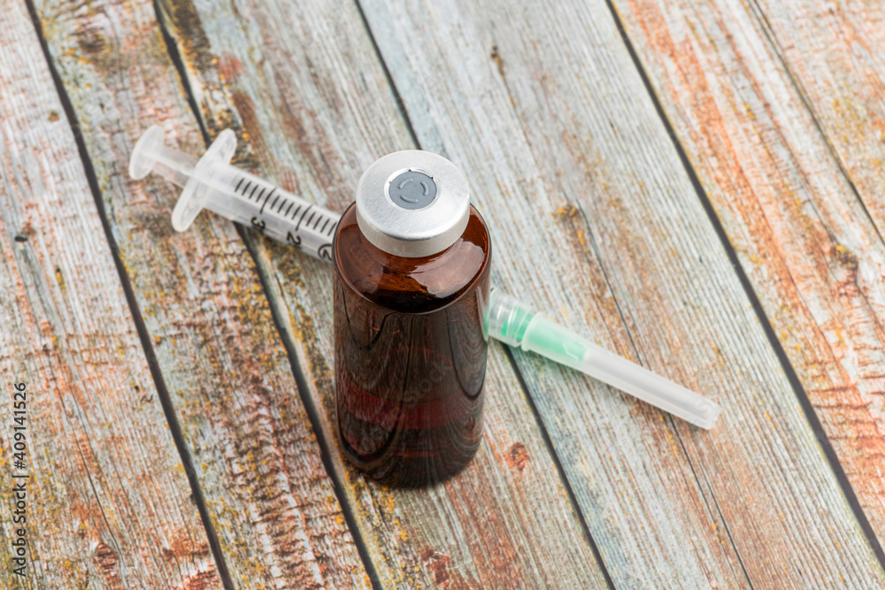 Disposable Syringe And Amber Color Vial On Wood Background