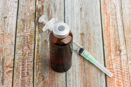 Disposable Syringe And Amber Color Vial On Wood Background photo