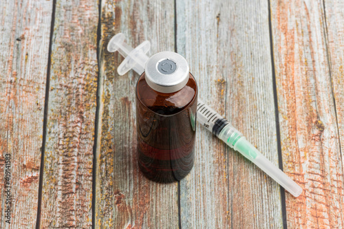 Disposable Syringe And Amber Color Vial On Wood Background photo