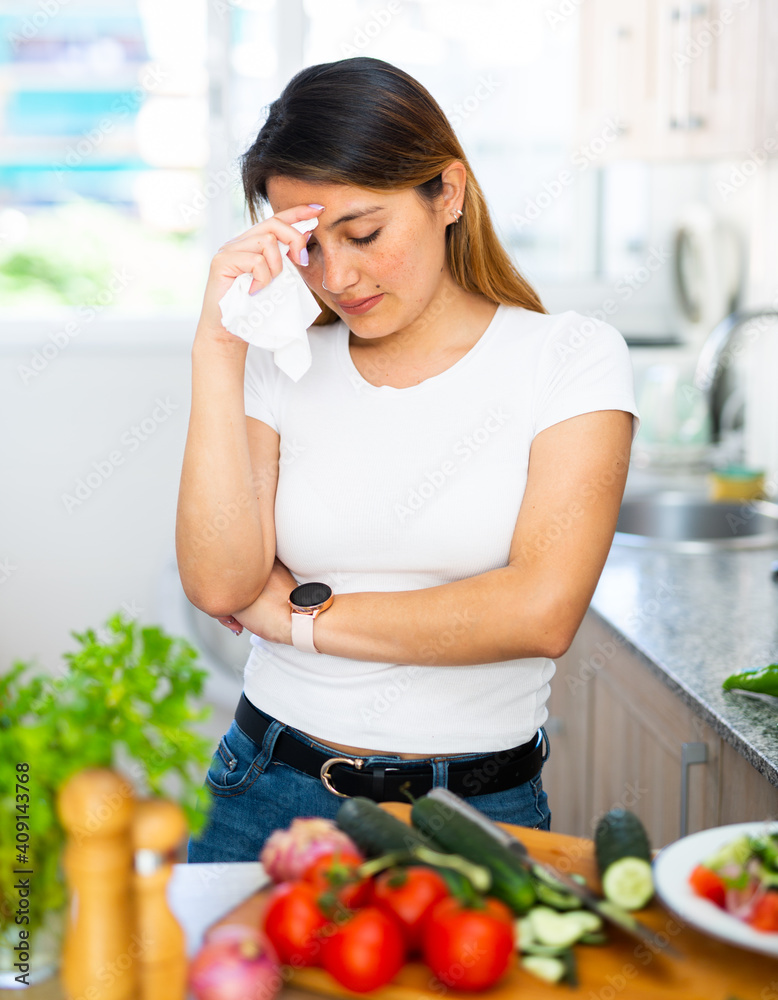 Unhappy mexican housewoman crying during cooking at kitchen