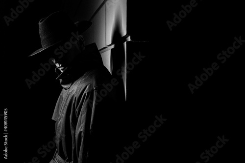 Photography dark silhouette of a man in a raincoat with a hat at night