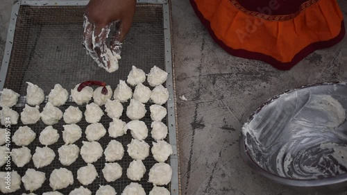 Indian woman is preparing Daler bori on a net in sunny day. It is a form of dried lentil dumplings popular in Bengali cuisine. photo