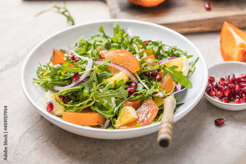 Delicious persimmon salad with arugula  and orange served on light grey table, flat lay. Space for text