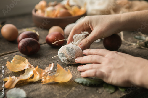 Eco decor. Easter eggs boiled in onions peels. Spring festive easter autentic background. Female hand  holds an egg on a wooden table close-up.