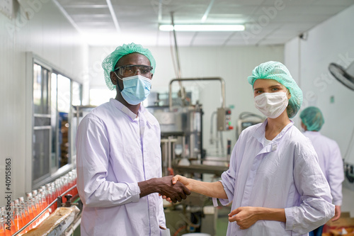 African and Caucasian Lab Specialist shake hand for cooperation in quality assurance of production in beverage industry