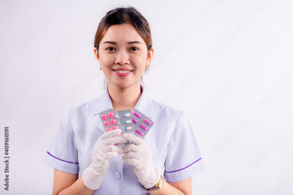 Young asian nurse holding a medicine capsule in her hand isolated on gray background