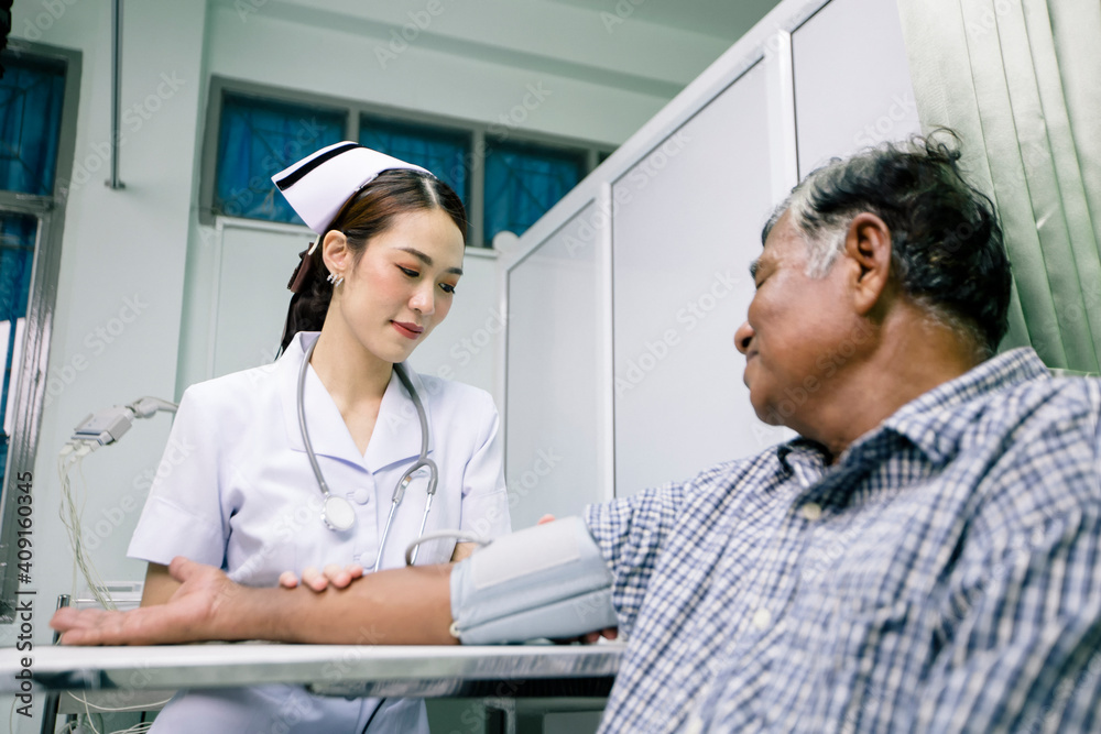 Young Asian nurse in uniform is measuring the pressure of senior man in a hospital. Young Asian nurse in uniform is measuring the pressure of senior man in a hospital.