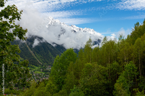 View of the French Alps near the summit of Mont Blanc at the entrance of the Mont Blanc Tunnel between France and Italy. There is a thick forest, snowy mountain tops, cottages on the foothills. photo