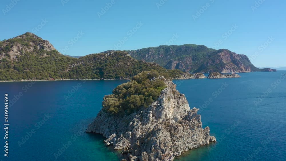 Rock Island in the sea on background of mountains in blue bay Marmaris, Icmeler Turkey. Aerial view 4K. Rock Island in the sea on background of mountains in blue bay Marmaris, Icmeler Turkey. Aerial view 4K.