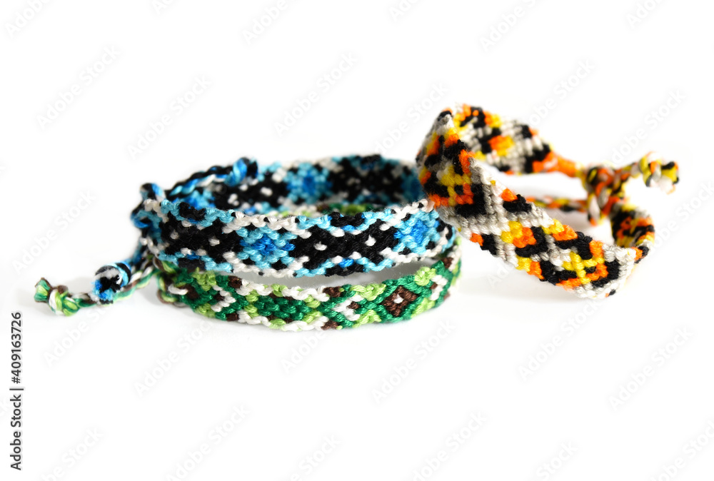 Fototapeta premium Selective focus of tied woven friendship bracelets with bright colorful patterns handmade of thread isolated on white background