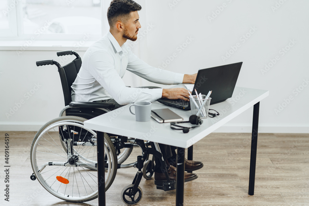 Disabled man in a wheelchair using laptop Disabled man in a wheelchair using laptop