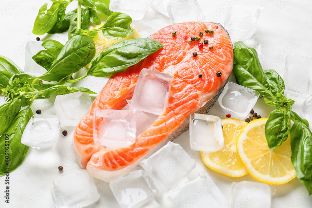 Raw salmon steak, lemon and ice cubes on light background Raw salmon steak, lemon and ice cubes on light background