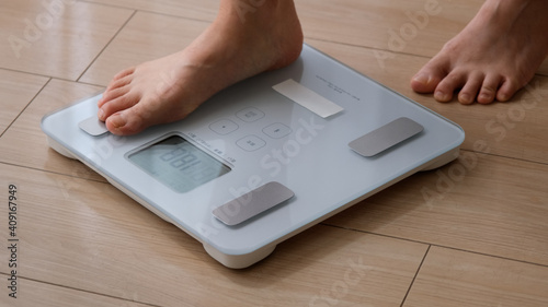 白い体重計に乗る女性