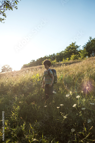 A boy with a backpack walks in the meadow © zhukovvvlad