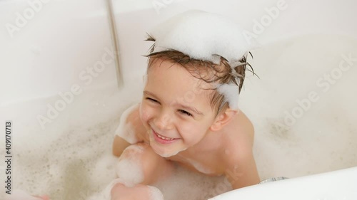 Closeup of young mother playing with her little son taking bath and washing hair with shampoo. Concept of child hygiene and health care at home. Family having fun and playing. at home