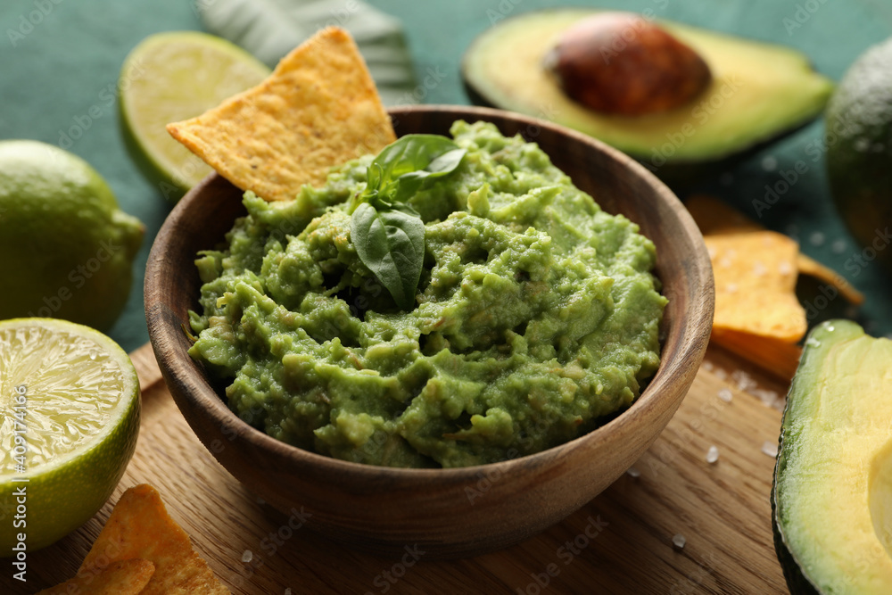 Concept of tasty eating with bowl of guacamole on green textured background Concept of tasty eating with bowl of guacamole on green textured background