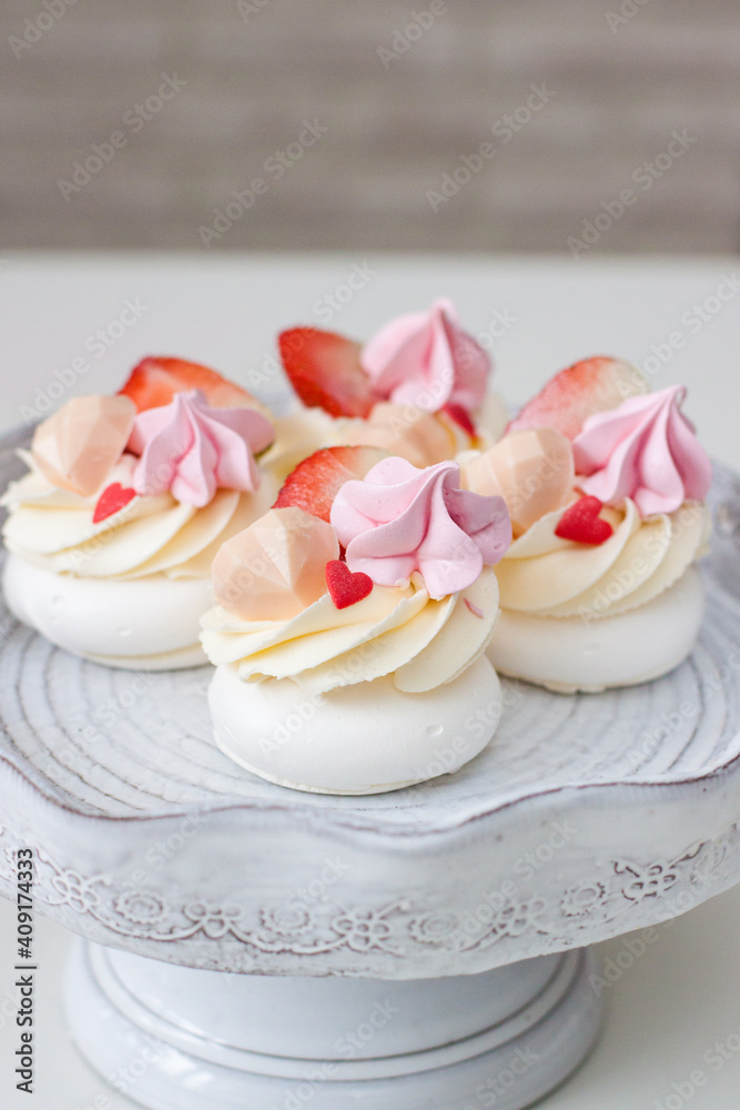 Mini pavlova cakes with chocolate hearts, fresh strawberries and red heart shaped sprinkles