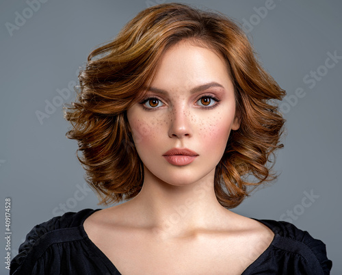 Beautiful brown haired with stylish short hairstyle. Woman with a  curly hair. Beautiful young woman with freckles on face.  Closeup portrait of an attractive girl  with a brown makeup. photo