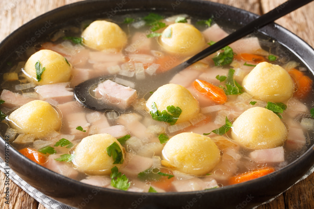 Delicious Liechtenstein cuisine soup with ham and cornmeal dumplings close-up in a plate on the table. horizontal Delicious Liechtenstein cuisine soup with ham and cornmeal dumplings close-up in a plate on the table. horizontal