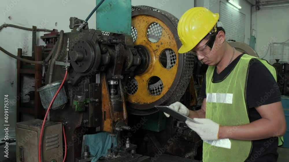 An Asian male engineer or worker is inspecting and repairing machines in the factory. Engineering and industrial concept. An Asian male engineer or worker is inspecting and repairing machines in the factory. Engineering and industrial concept.