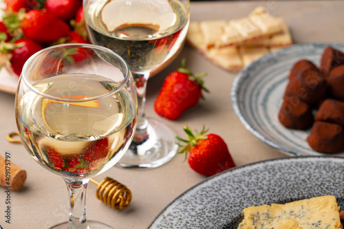 Glass of white wine, truffel chocolates and strawberry close up