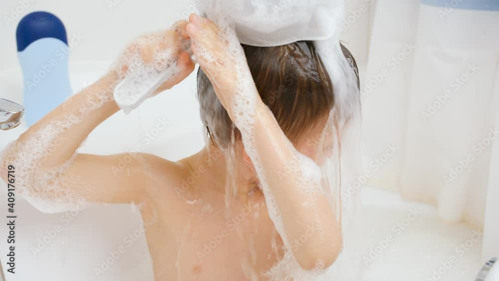 Slow motion of little boy washing head from plastic bucket while having bath. Concept of child hygiene and health care at home. Child having fun and playing at home. Slow motion of little boy washing head from plastic bucket while having bath. Concept of child hygiene and health care at home. Child having fun and playing at home.