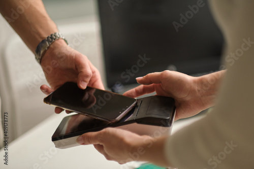 NFC technology. Customer is paying. Close up of guest using smart phone while making contactless payment in a pub.