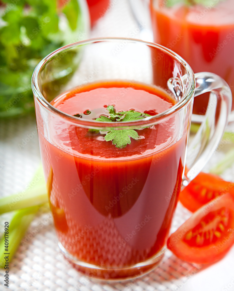 Fresh tomato juice with celery and parsley in a glass on a white table. Vitamins, natural, healthy drink for breakfast. Fresh tomato juice with celery and parsley in a glass on a white table. Vitamins, natural, healthy drink for breakfast.