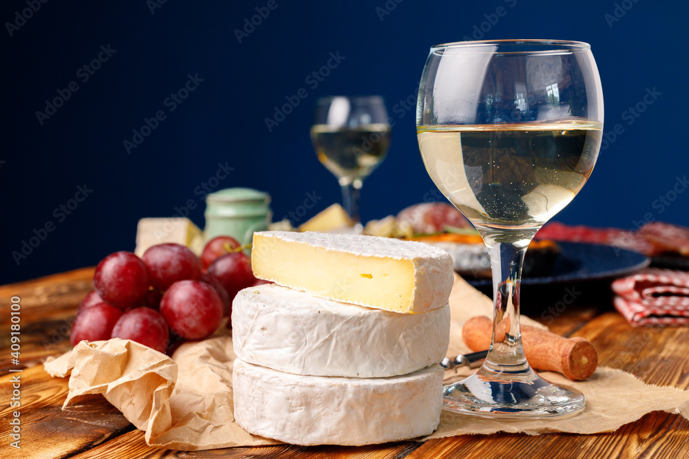 Round white cheese with grapes on wooden table