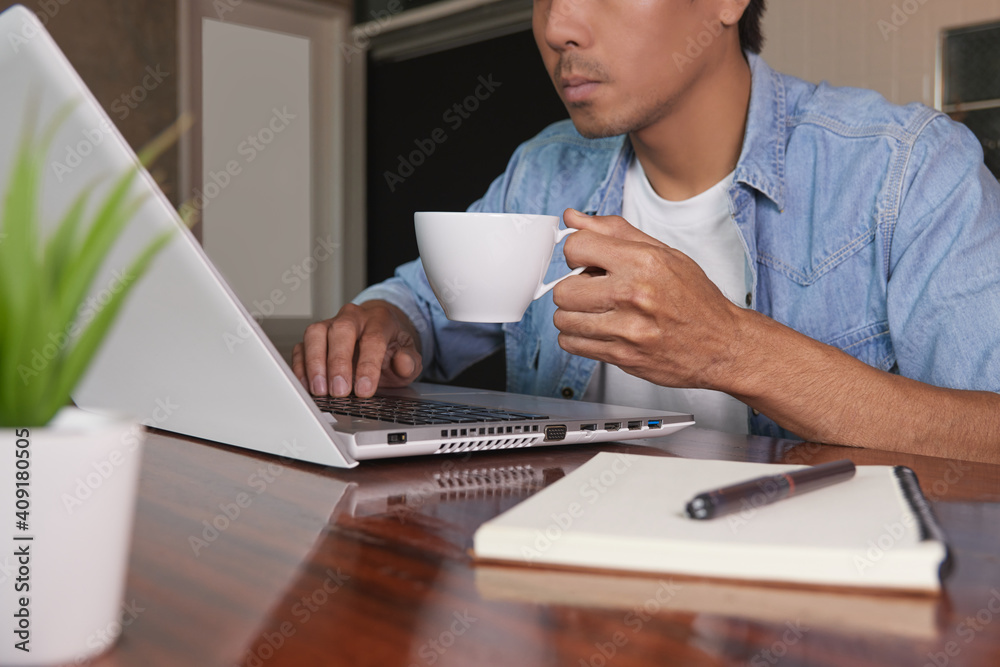 Zoom View Casual Businessman in Denim or Jeans Shirt Using Laptop and Hold Coffee Cup in Coffee Shop. Casual Businessman with Technology Zoom View Casual Businessman in Denim or Jeans Shirt Using Laptop and Hold Coffee Cup in Coffee Shop. Casual Businessman with Technology