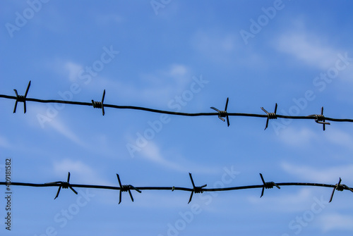 Close-up of barbed wire against the blue sky.