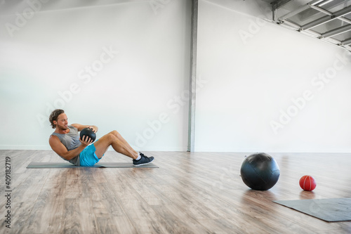 Gym medicine ball workout abs exercise at home. Man working out core body with weighted russian twists exercises training.