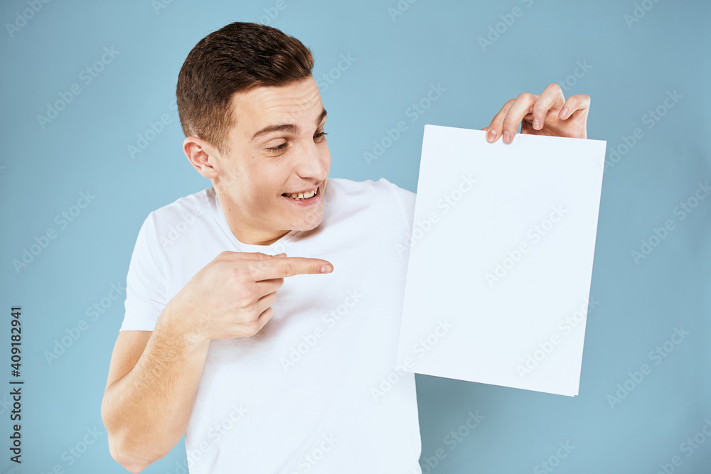 man holding a sheet of paper in his hands white t-shirt cropped view blue background man holding a sheet of paper in his hands white t-shirt cropped view blue background